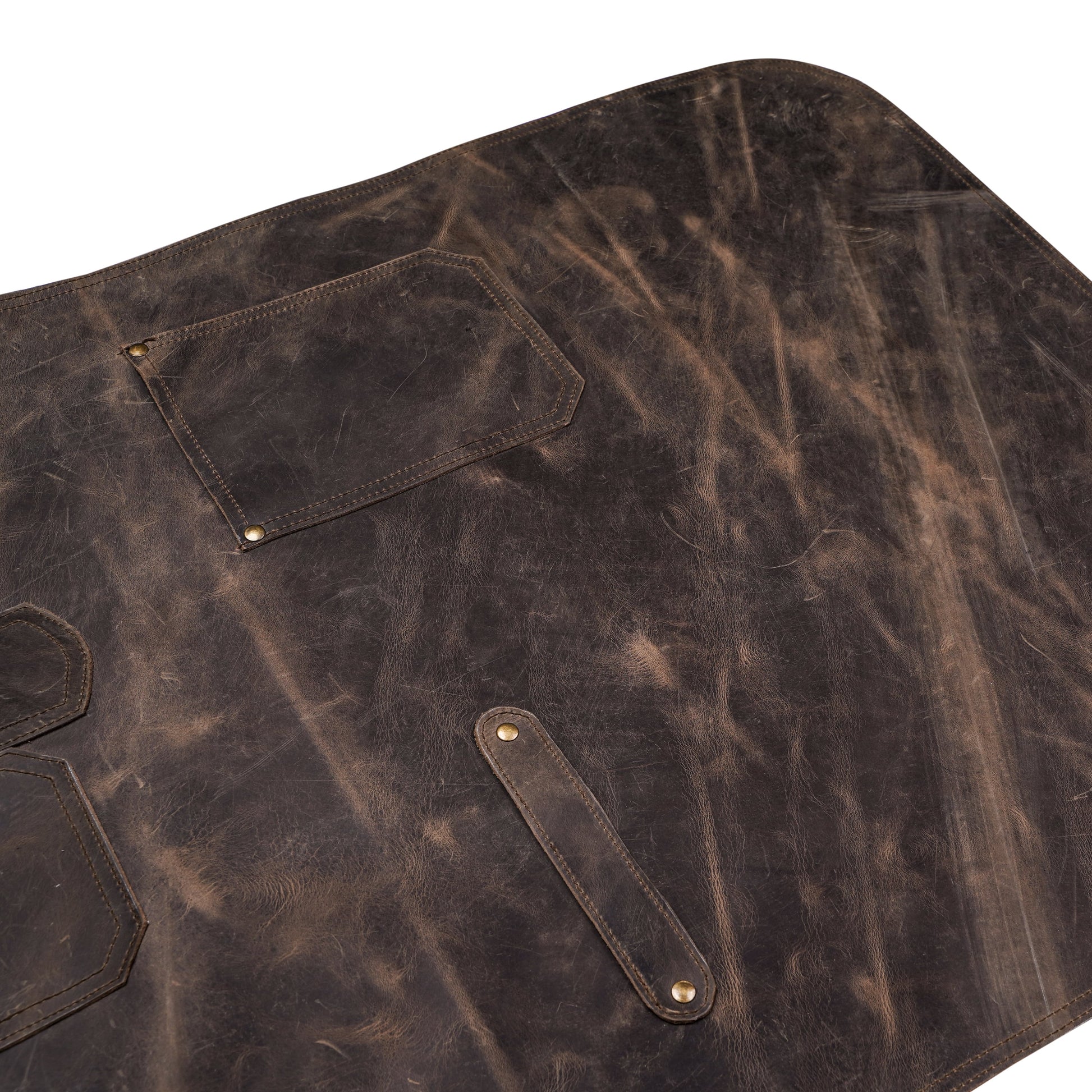 Close-up image of handcrafted pullup leather chef apron, focusing on leather texture, reinforced stitching, and brass buckle detailing. Captures premium craftsmanship, ideal for showcasing personalization area. Great for chefs, BBQ pros, and hairstylists looking for functional and elegant workwear.

