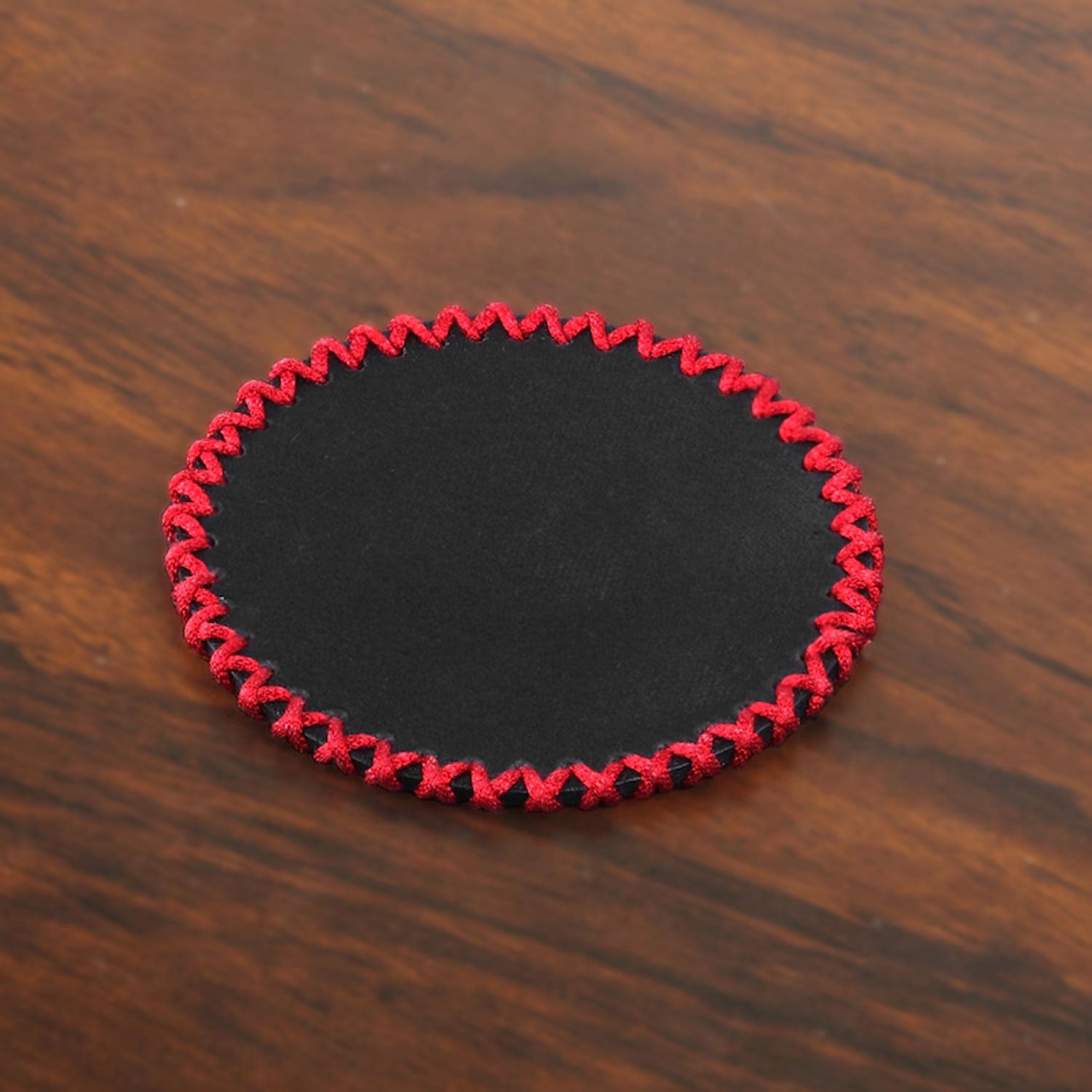 Detailed close-up view of the handknitted lace stitching around the leather coaster edge, showcasing craftsmanship, thread variety, and premium cowhide surface texture.

